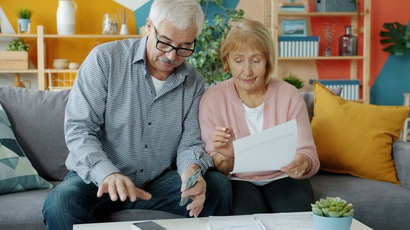An older couple reviews household papers together on a sofa