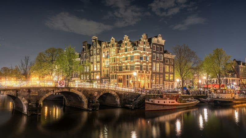 Historic Amsterdam canal houses and a bridge illuminated at night
