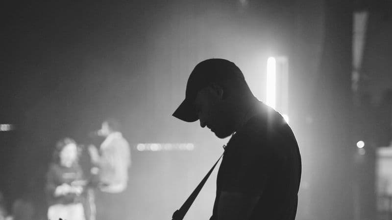 Guitarist performing backstage in silhouette under stage lights