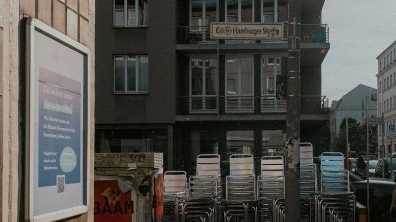 Stacks of café chairs stand outside a closed entrance on a Berlin street