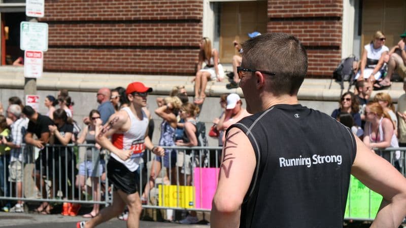 A Boston Marathon runner waits near the final stretch for another participant
