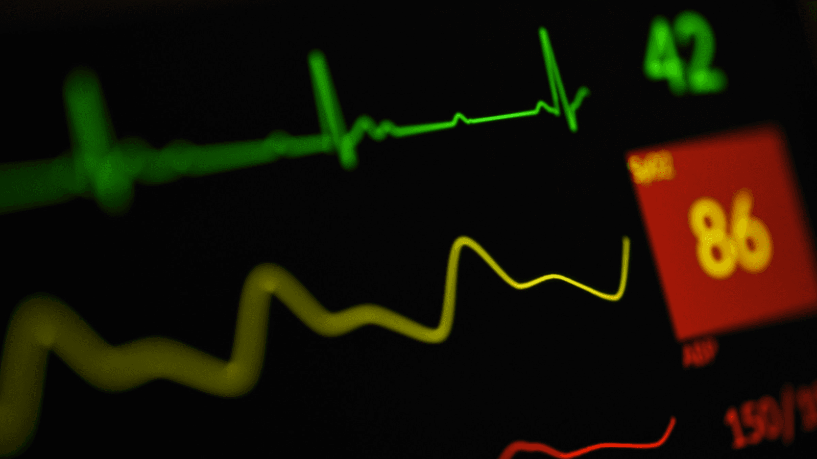Green heart rhythm and vital signs glowing on a hospital monitor