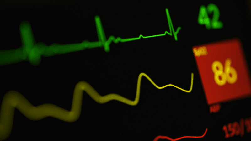 Green heart rhythm and vital signs glowing on a hospital monitor