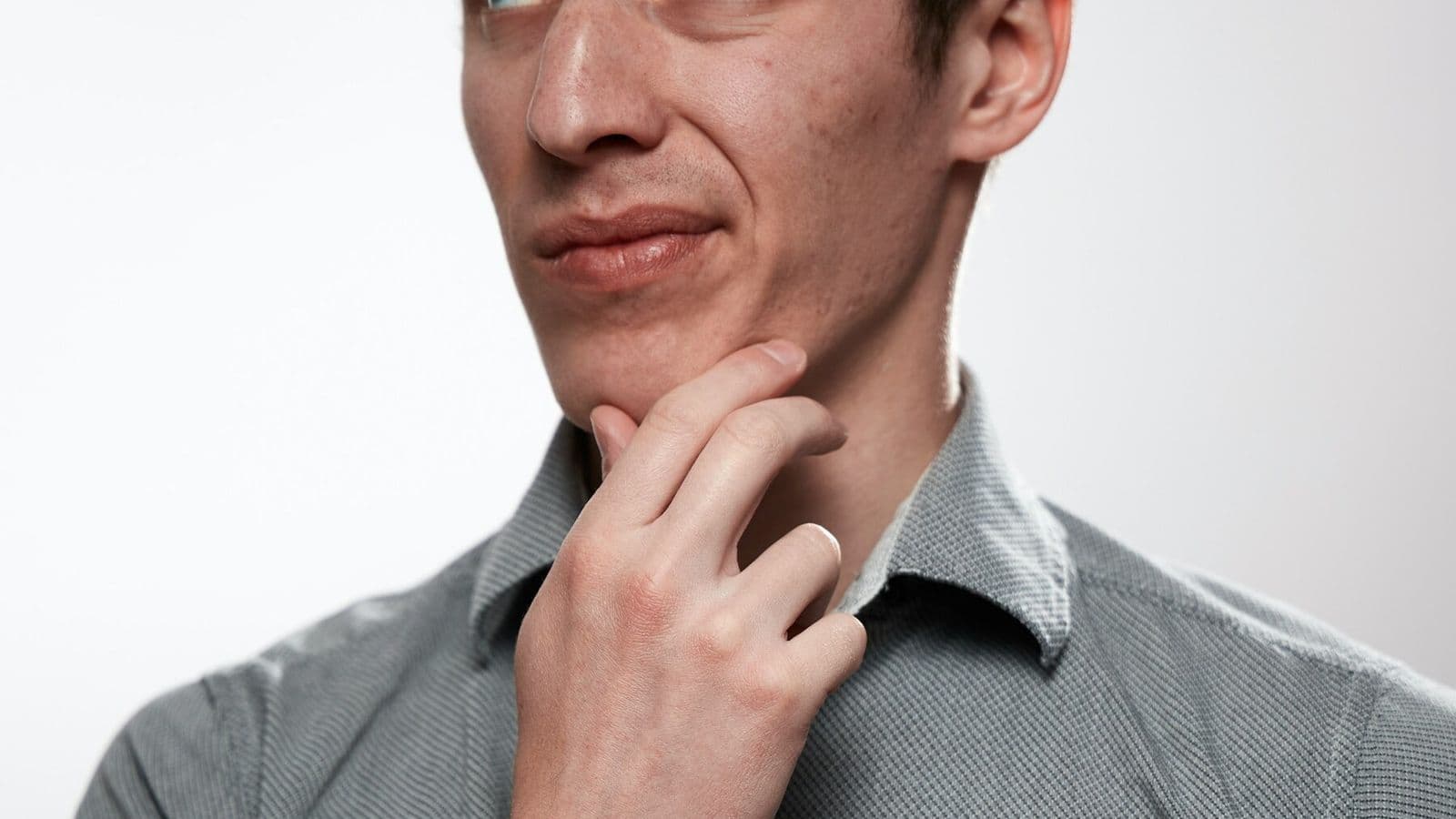 A thoughtful man pauses with his hand beneath his chin