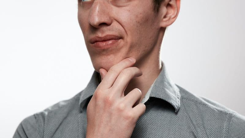 A thoughtful man pauses with his hand beneath his chin