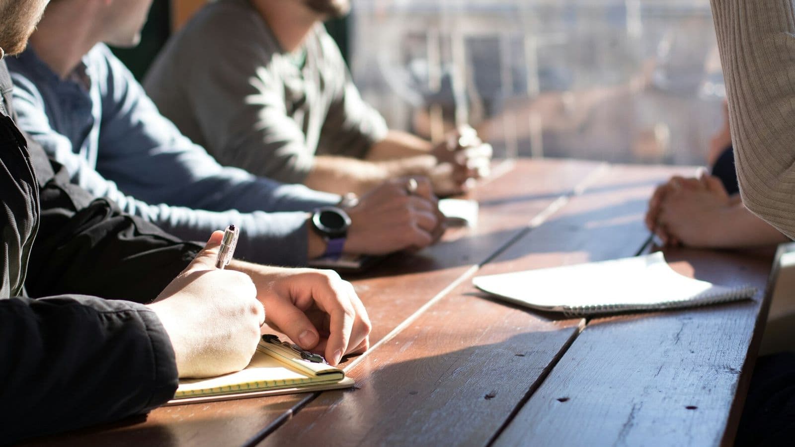 Colleagues listen and take notes around a meeting table
