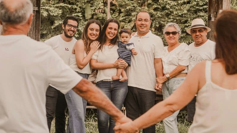 Several generations of a family hold hands in a circle outdoors