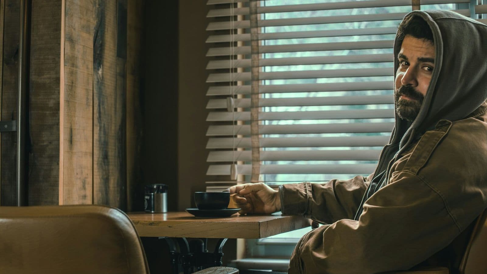 A man sits alone with a cup in a quiet café