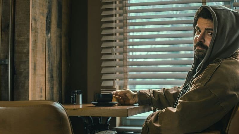 A man sits alone with a cup in a quiet café