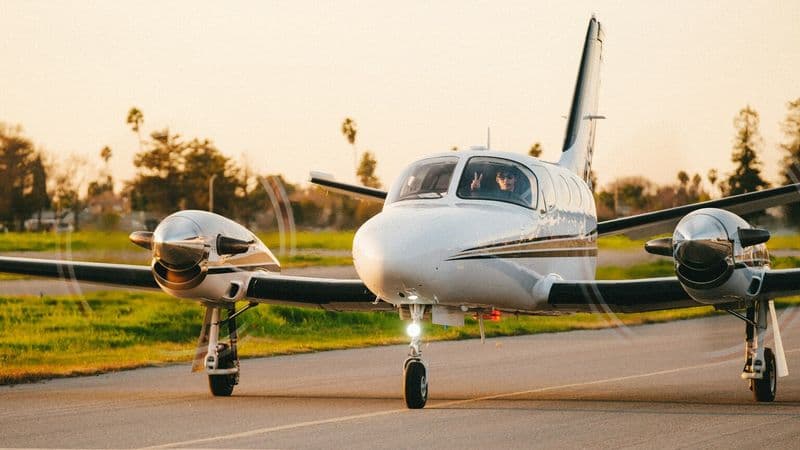 Small twin-engine plane taxiing on a California runway at golden hour