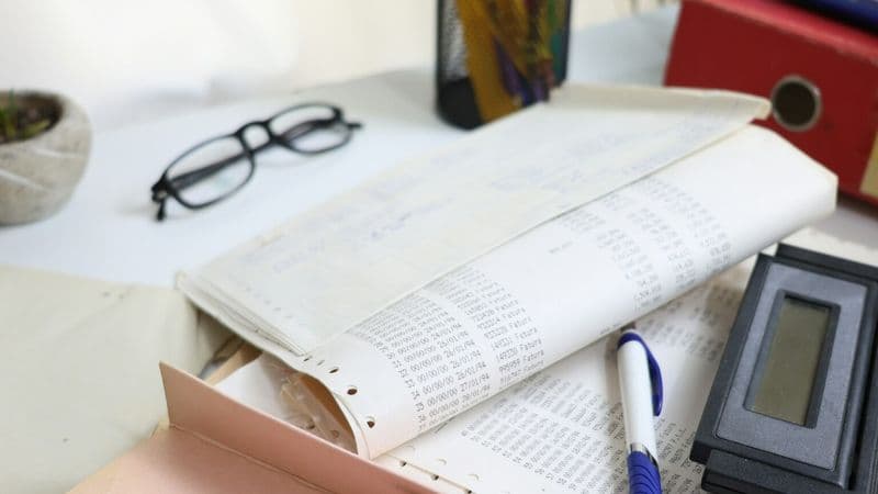 Paper financial records, calculator, pen and office folders on a desk